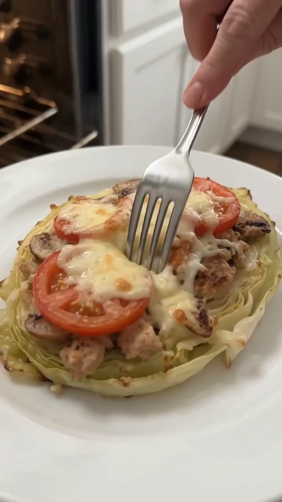 Loaded Cabbage Steaks with Ground Chicken and Mozzarella – A hand is using a fork to eat a dish