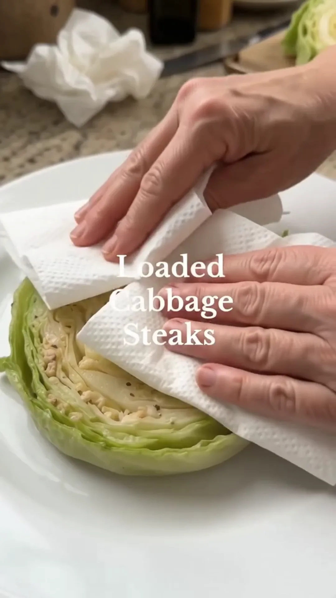Loaded Cabbage Steaks with Ground Chicken and Mozzarella – Someone is wiping a cabbage steak with a paper towel