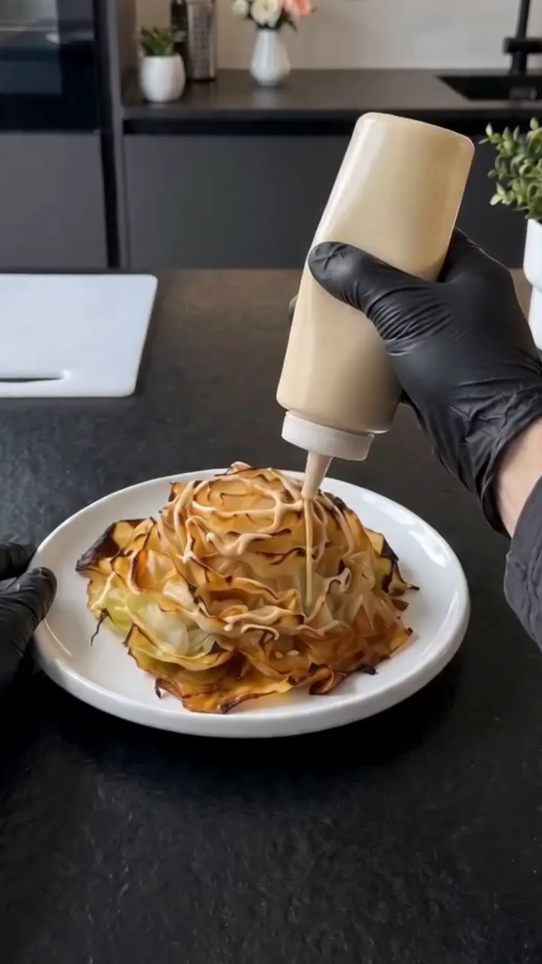 Miso Glazed Cabbage Flowers with Tahini and Cashews – applying sauce to a dish