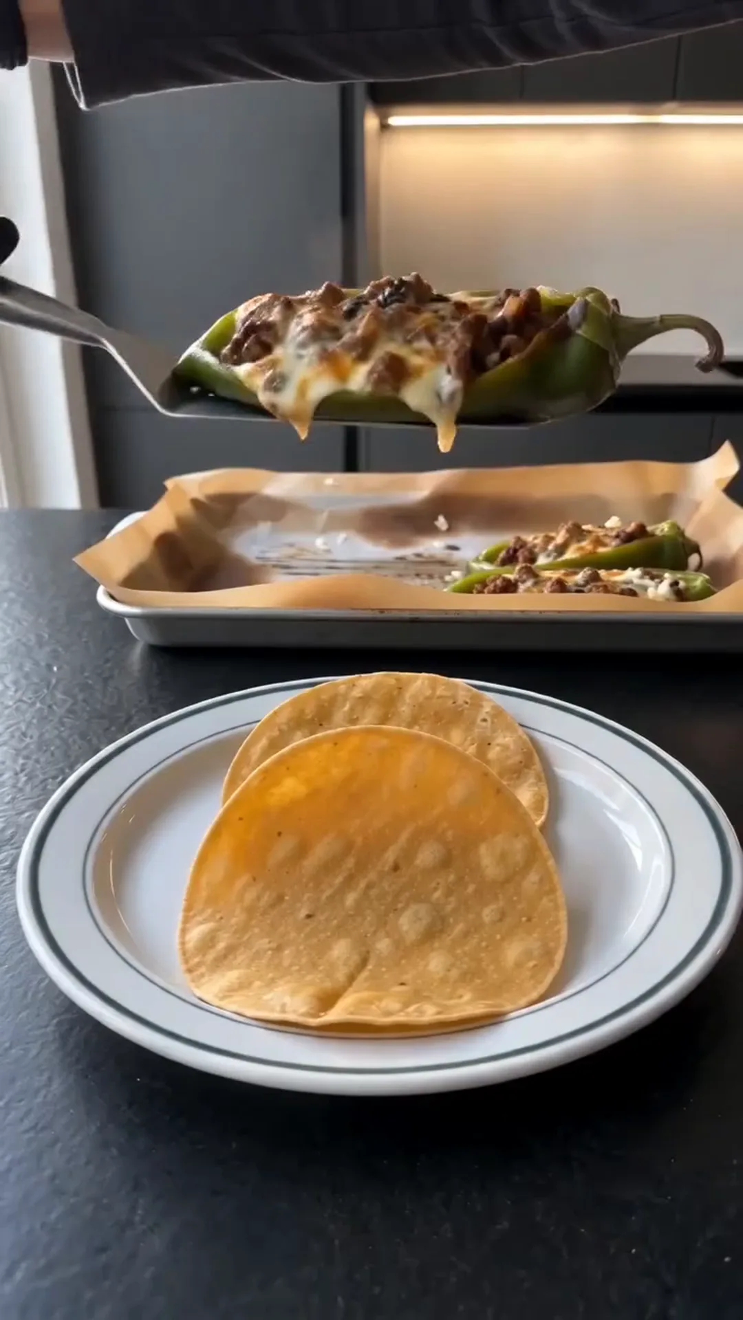 Roasted Anaheim Chile Tacos with Seasoned Beef and Cheese – A person is serving a stuffed pepper with melted cheese