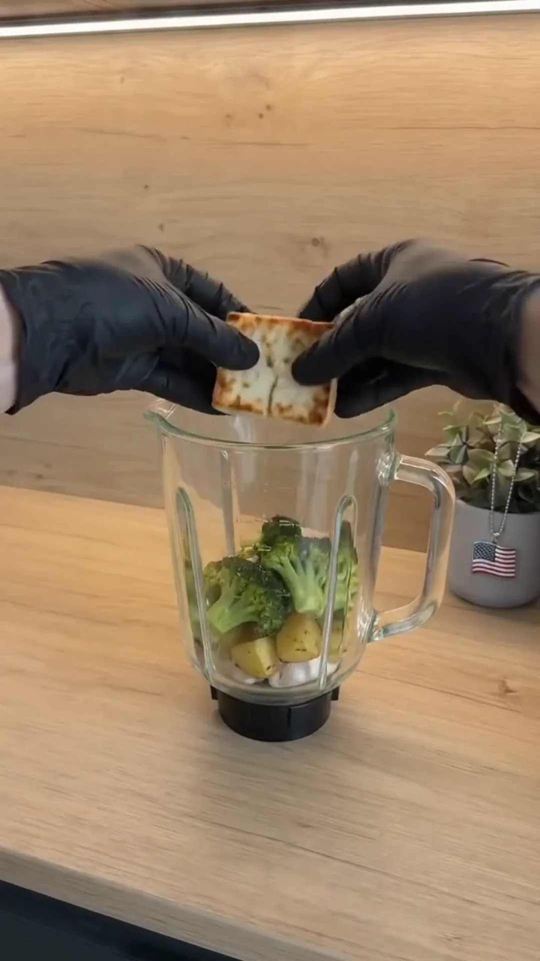 Roasted Broccoli and Feta Soup with Roasted Garlic – person putting crackers into a blender with vegetables