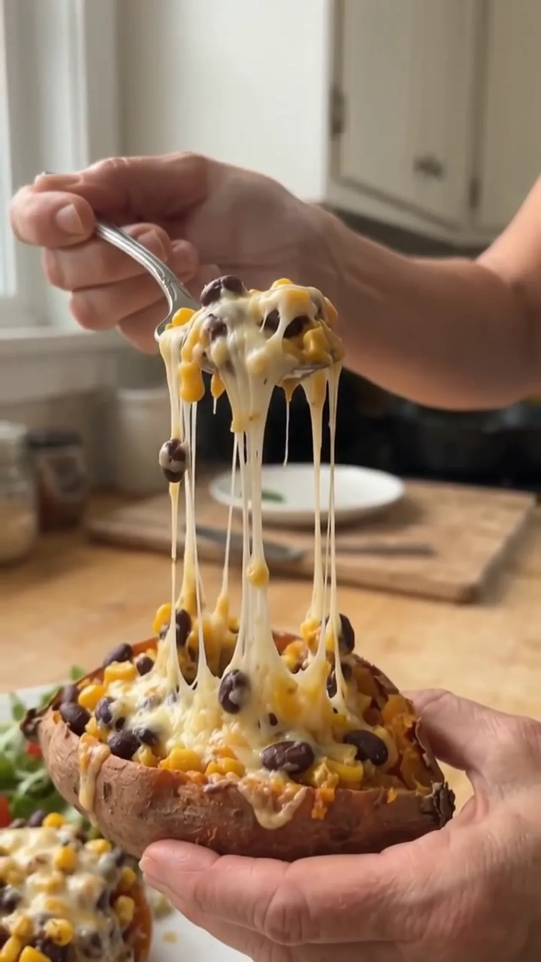 Roasted Stuffed Sweet Potatoes with Seasoned Beef and Corn – person is pulling cheese from a baked sweet potato