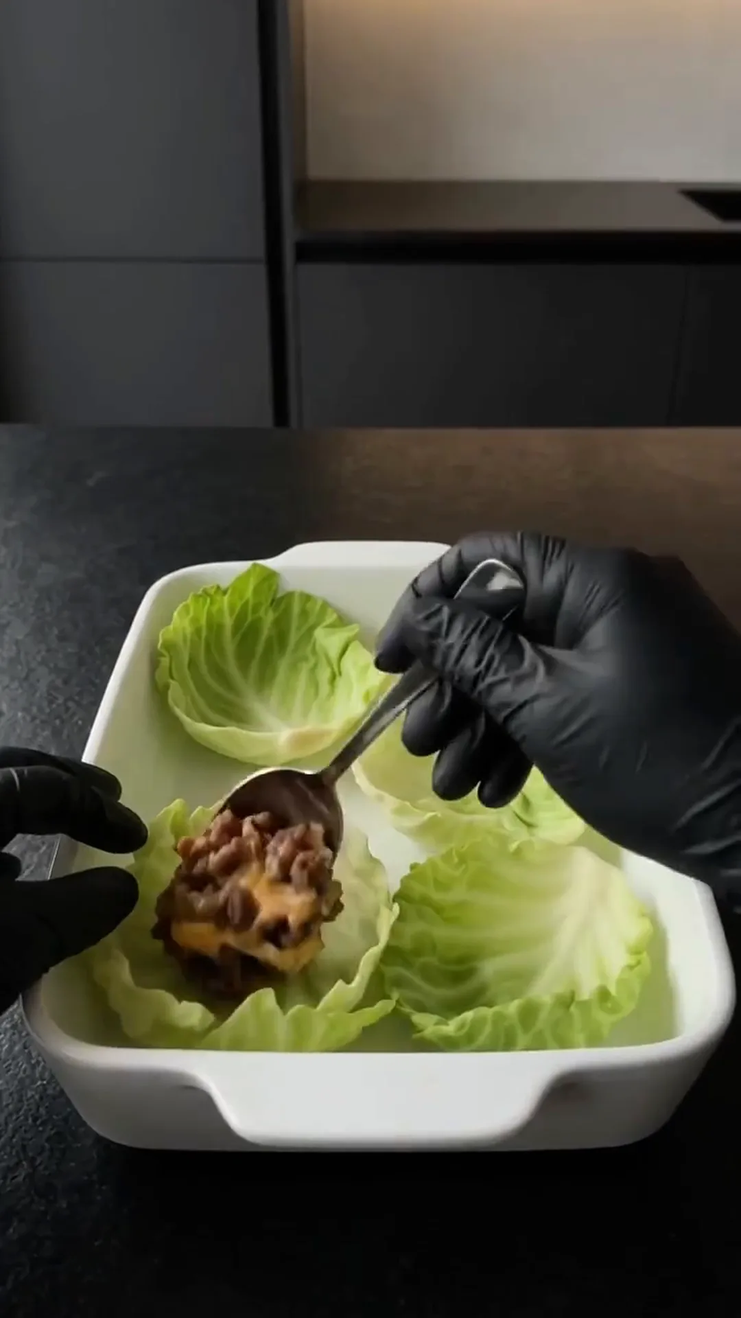 Savory Cheeseburger Cabbage Cups with Melted Cheese – person is preparing a lettuce wrap with a spoon