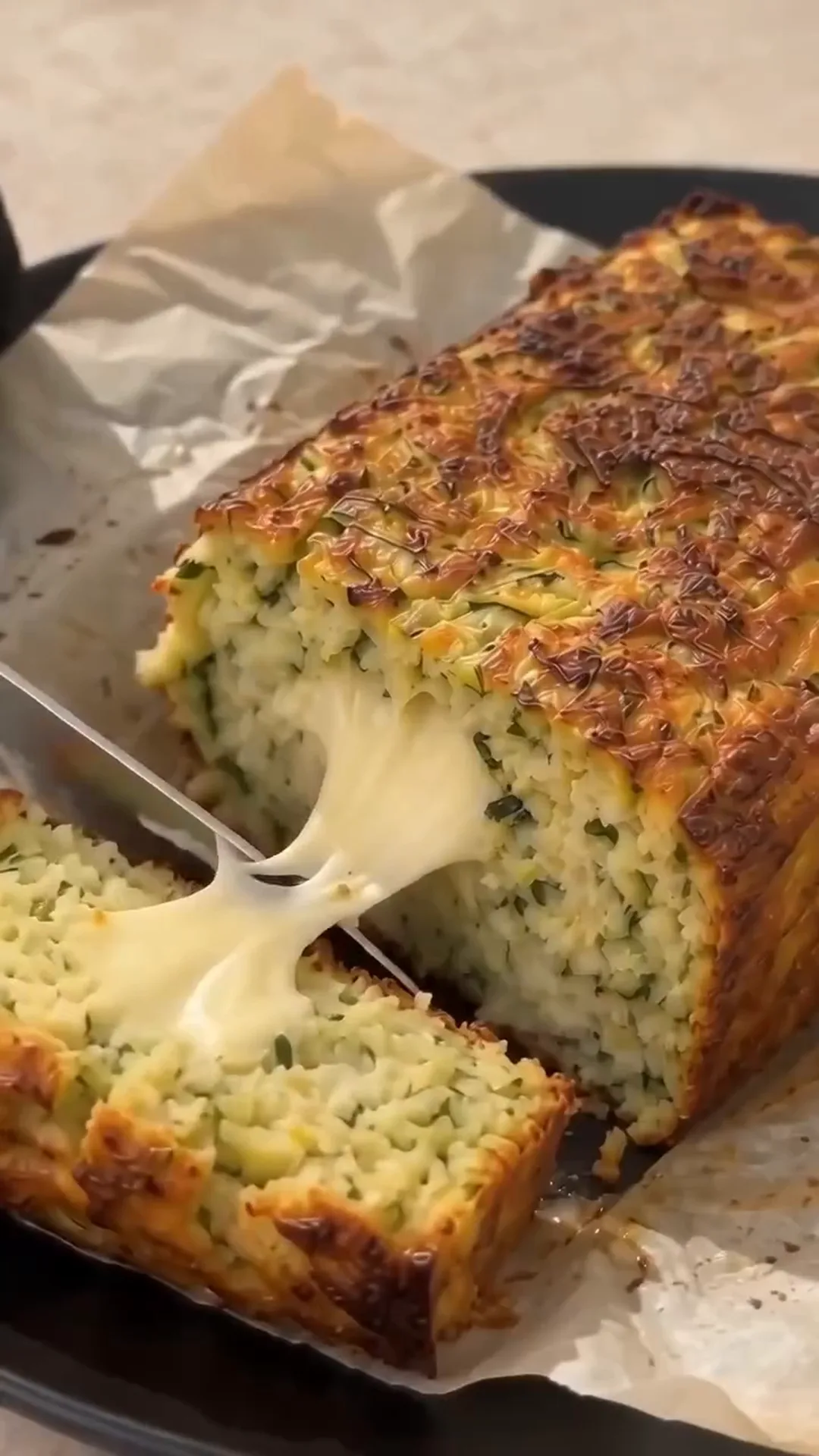 Savory Cheesy Baked Zucchini Loaf with Melted Center – pulling a slice of cheesy zucchini bread out of a loaf