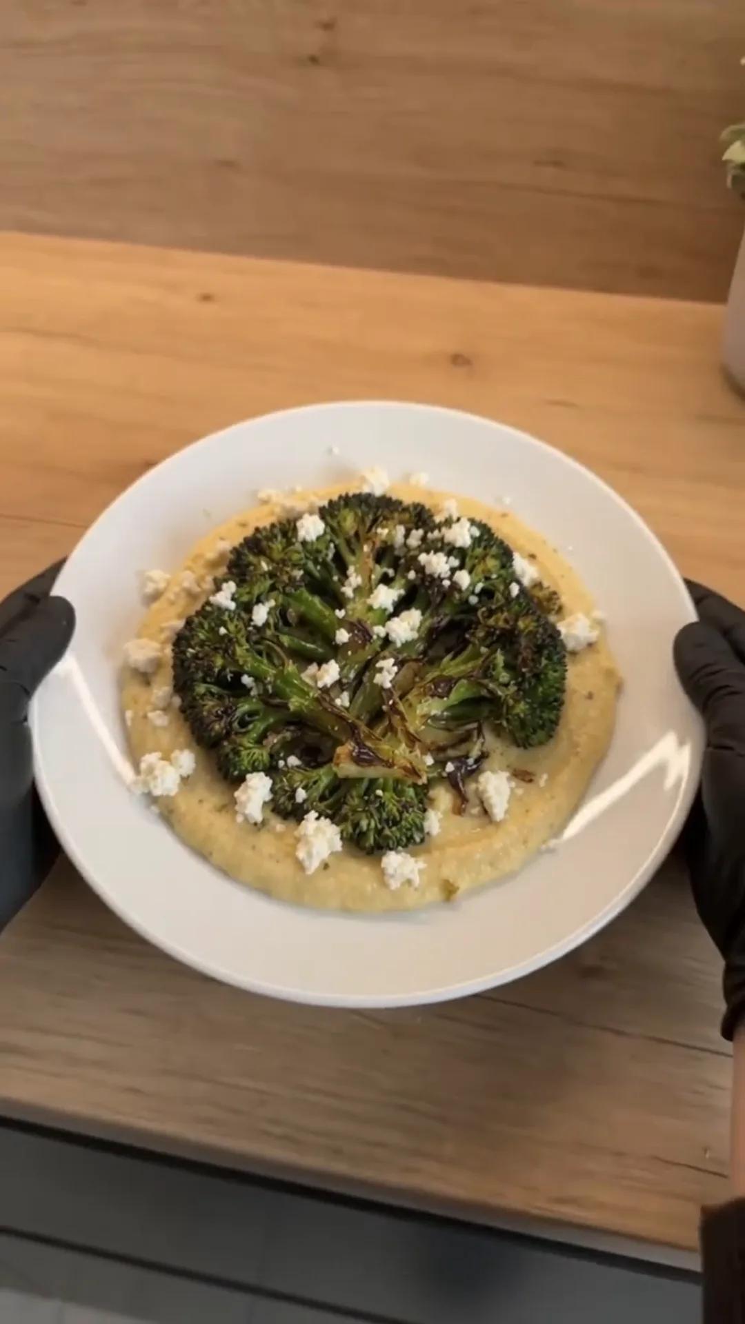 Seared Broccoli Steaks with Chimichurri and Butter Bean Purée – person holding a bowl of food, possibly adding cheese
