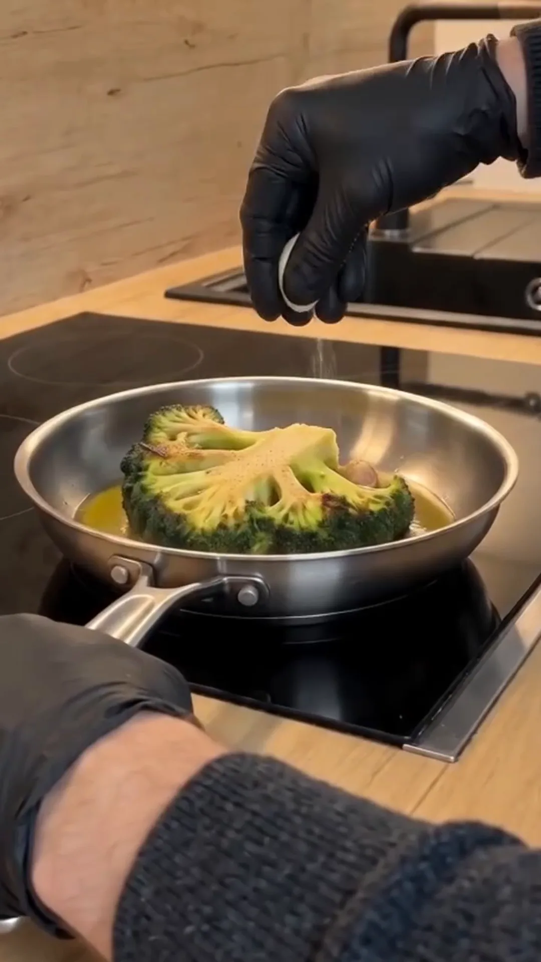 Seared Broccoli Steaks with Chimichurri and Butter Bean Purée – Spraying oil on a piece of broccoli in a pan