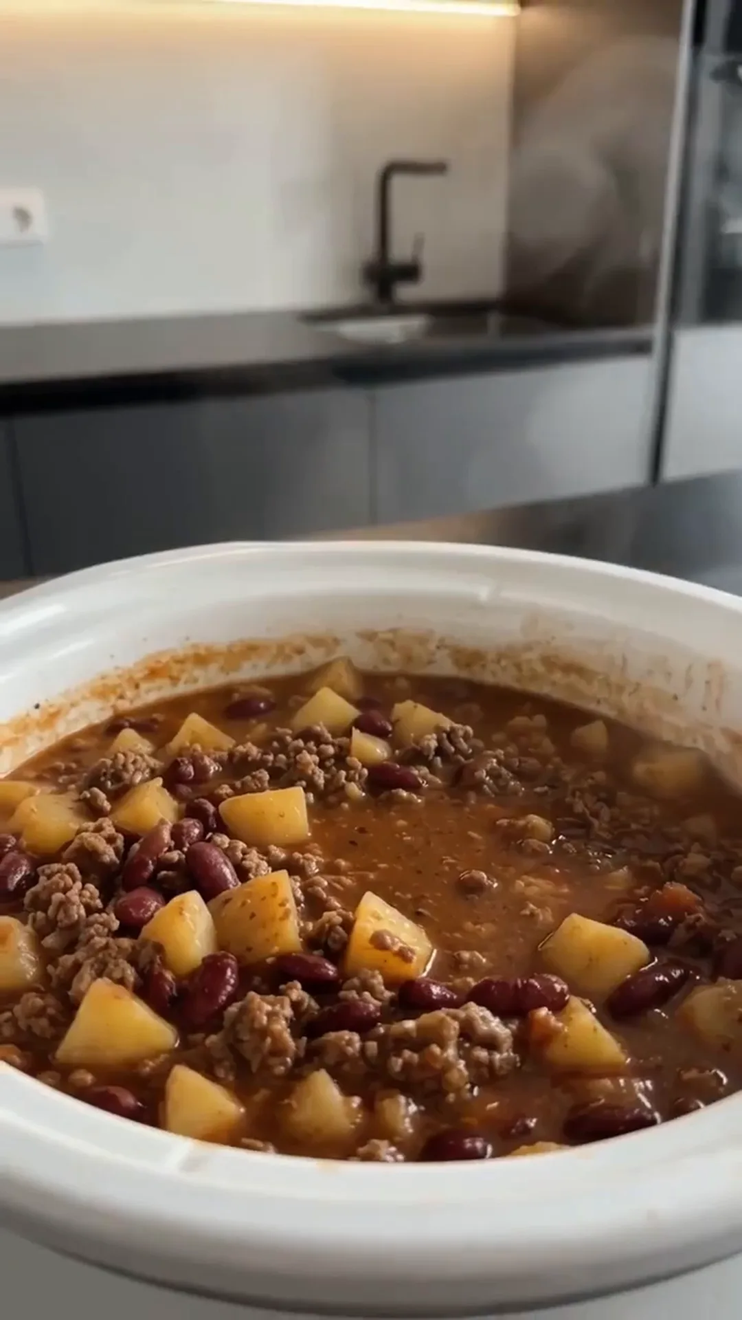 Slow Cooker Beef Potato and Bean Stew – a person is cooking a stew in a pot