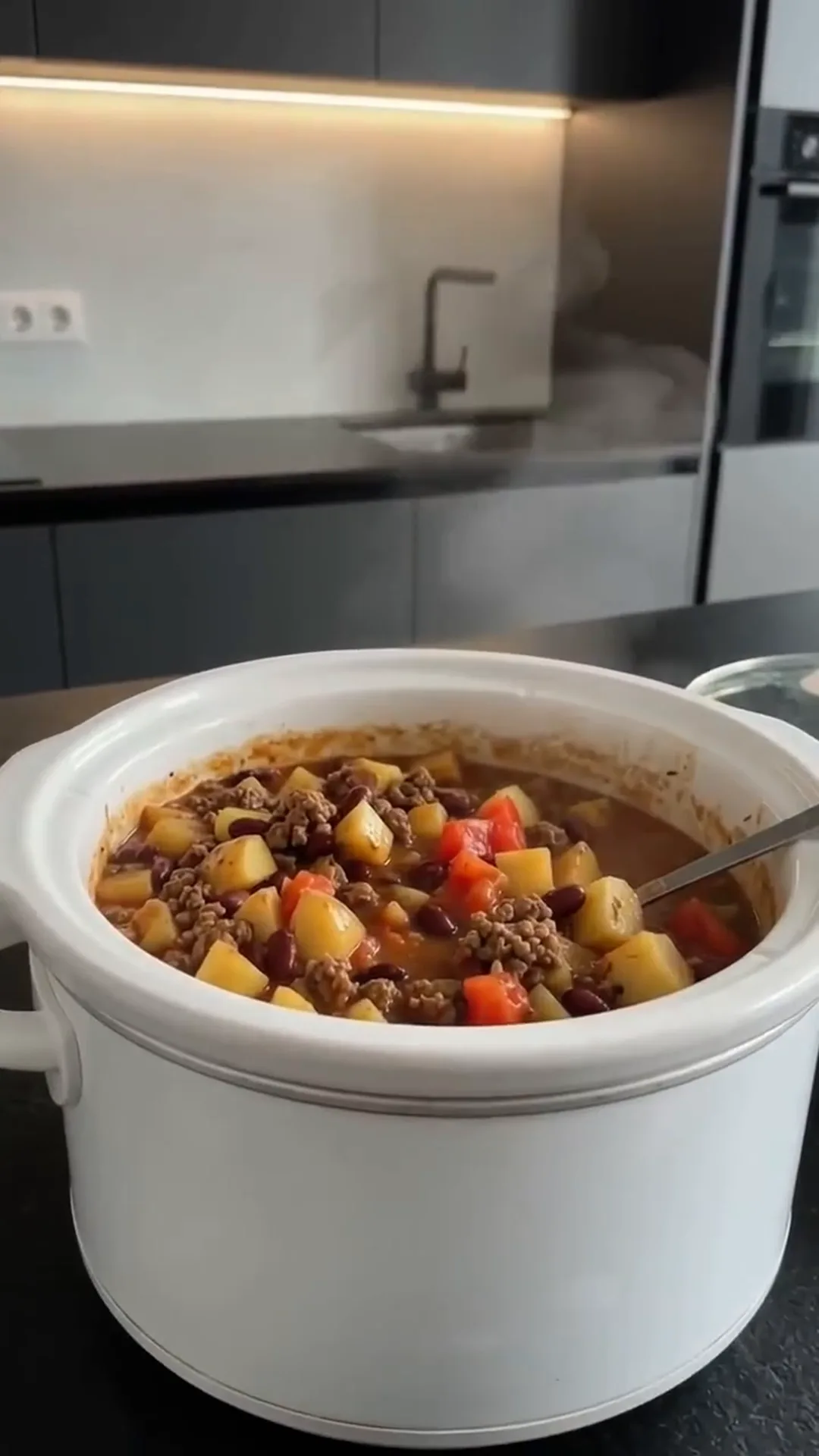 Slow Cooker Beef Potato and Bean Stew – someone is eating a stew from a crock pot