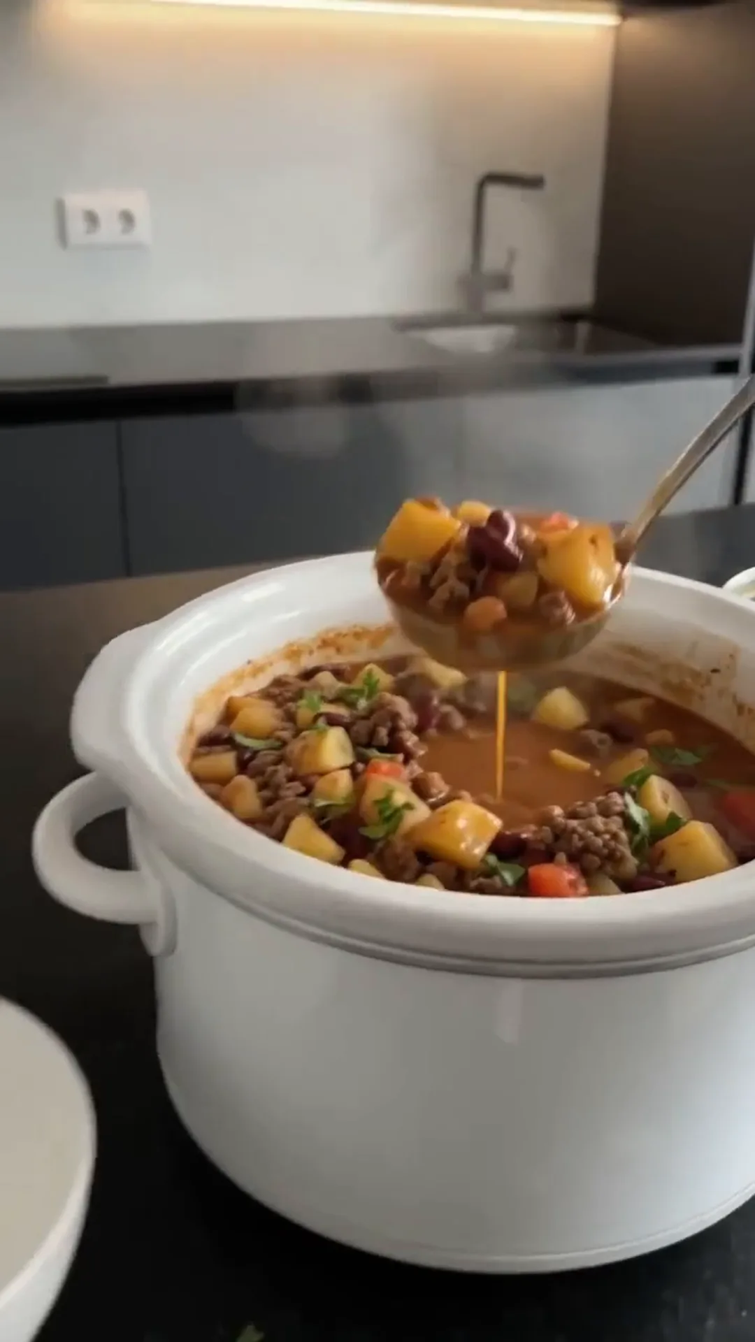 Slow Cooker Beef Potato and Bean Stew – A spoon is being used to serve a stew from a pot