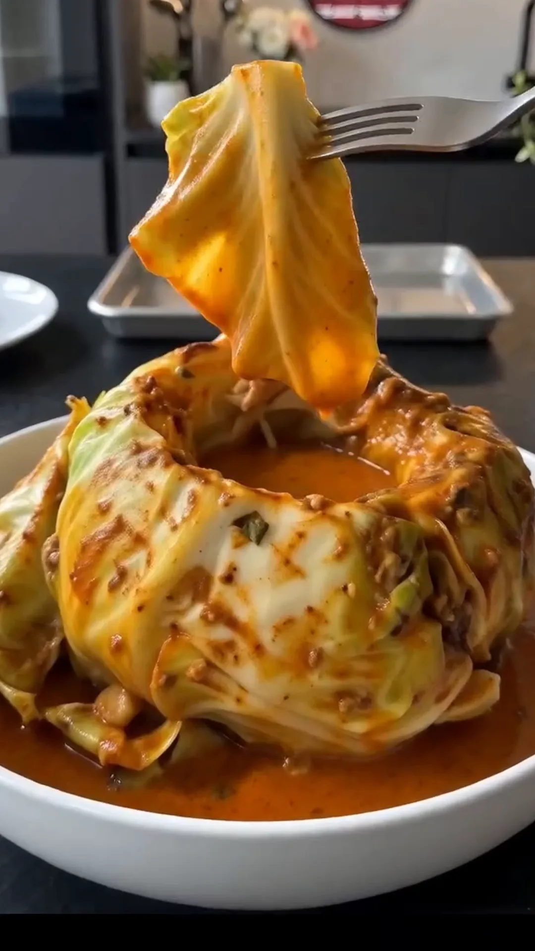 Slow Roasted Whole Cabbage with Savory Butter Sauce – A fork is lifting a piece of cabbage from a bowl of sauce