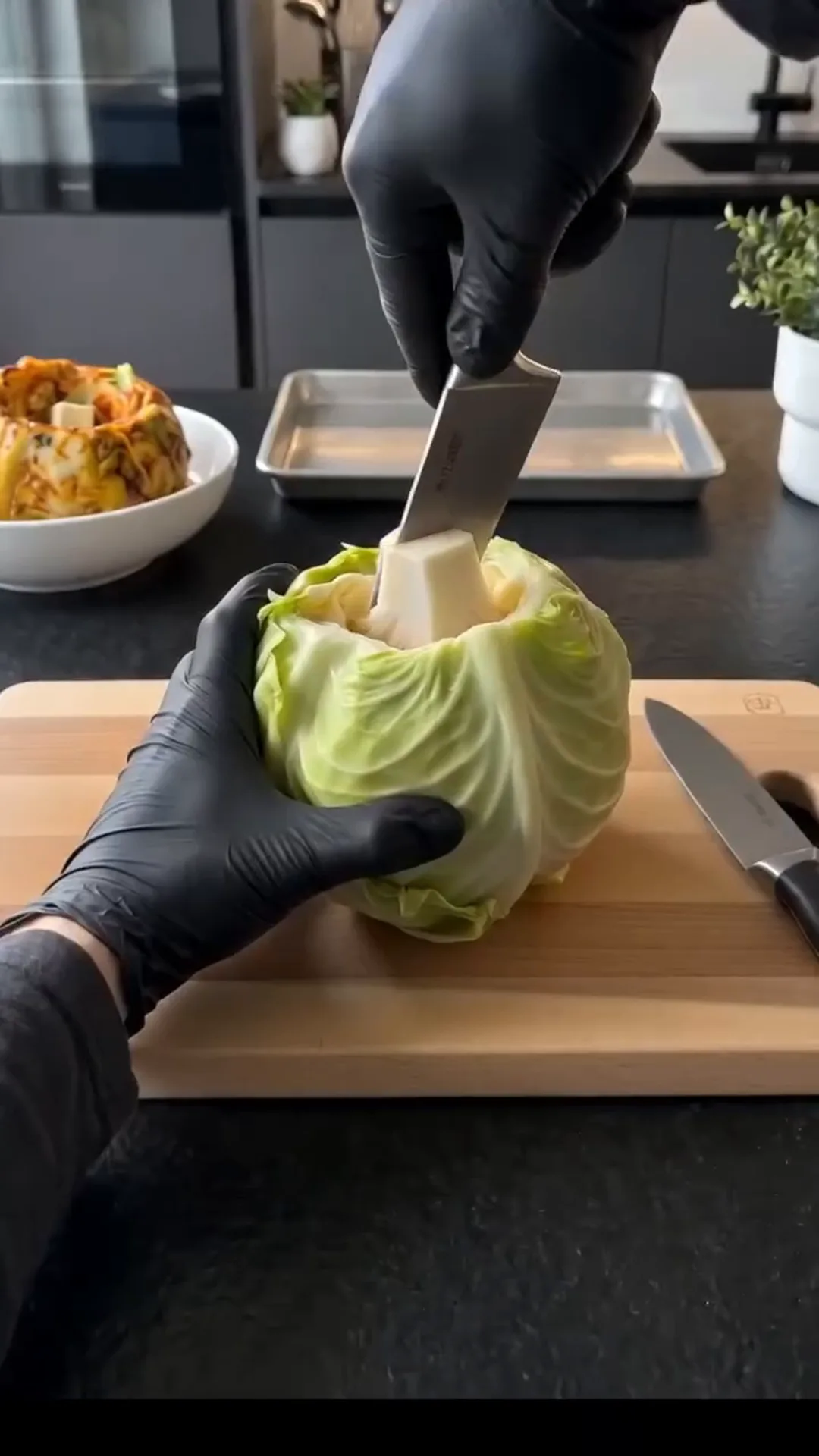 Slow Roasted Whole Cabbage with Savory Butter Sauce – Someone is cutting a head of lettuce with a knife