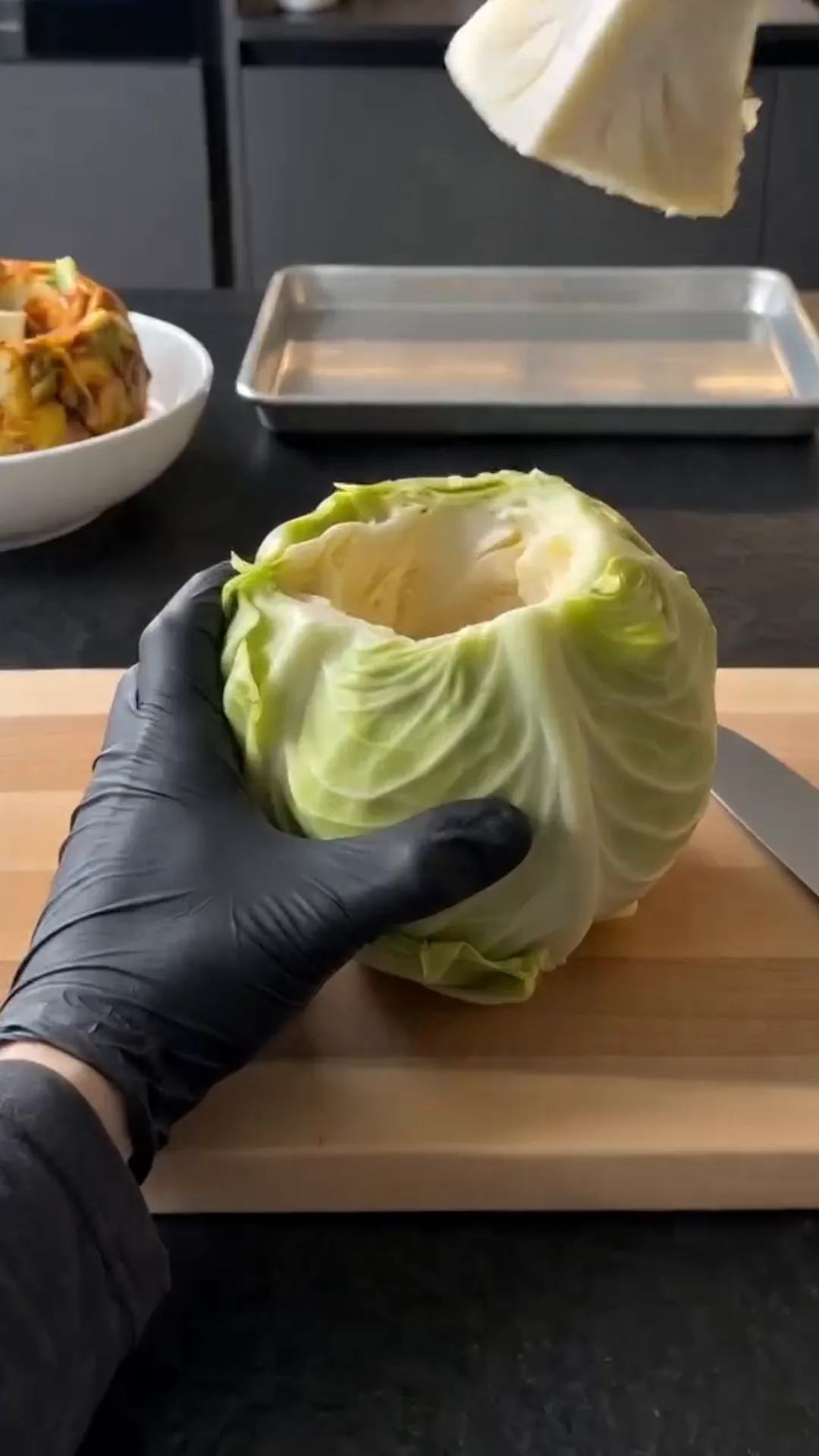 Slow Roasted Whole Cabbage with Savory Butter Sauce – A person is cutting a head of lettuce on a cutting board