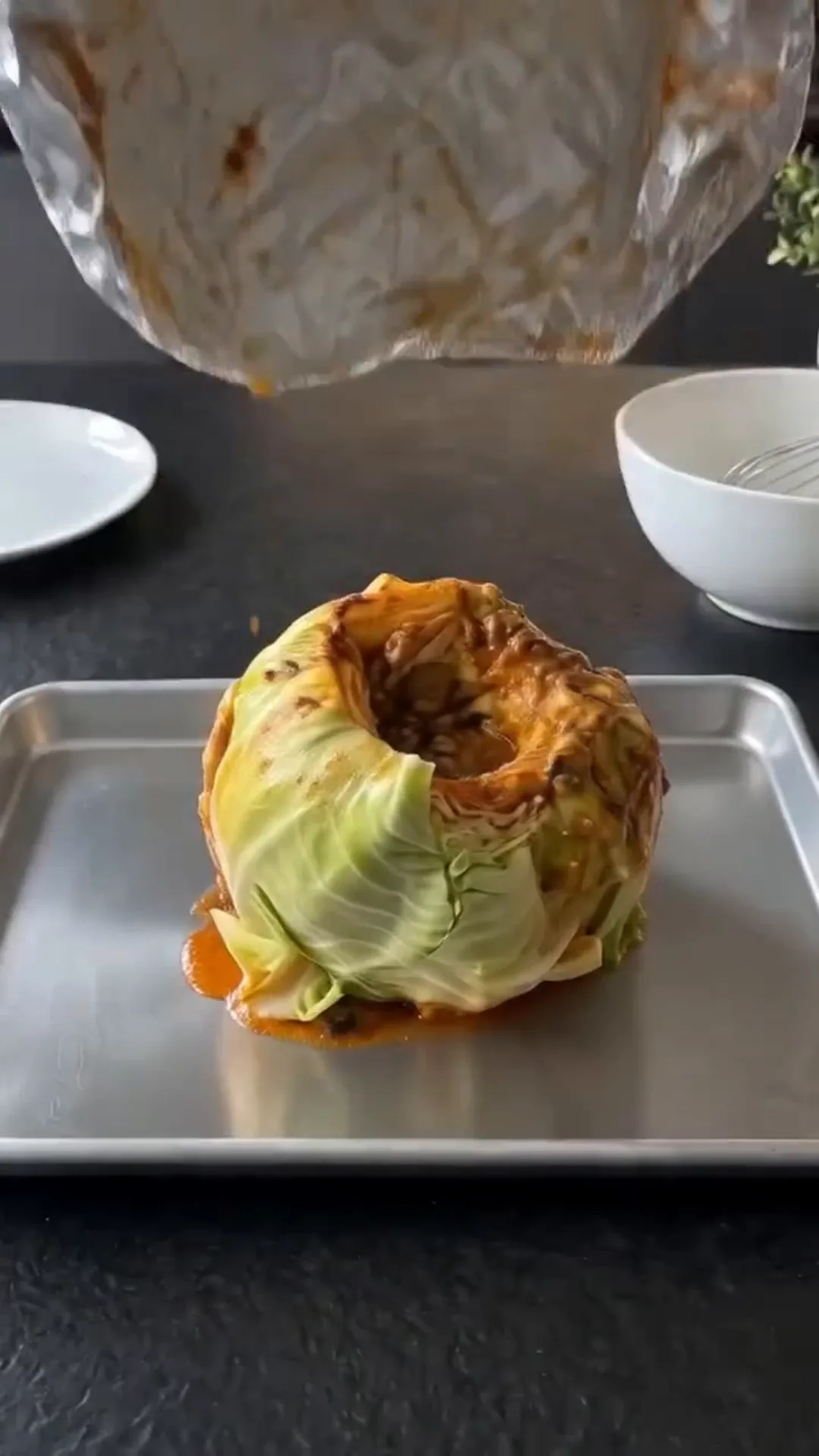 Slow Roasted Whole Cabbage with Savory Butter Sauce – Pouring sauce onto a cabbage head on a baking tray