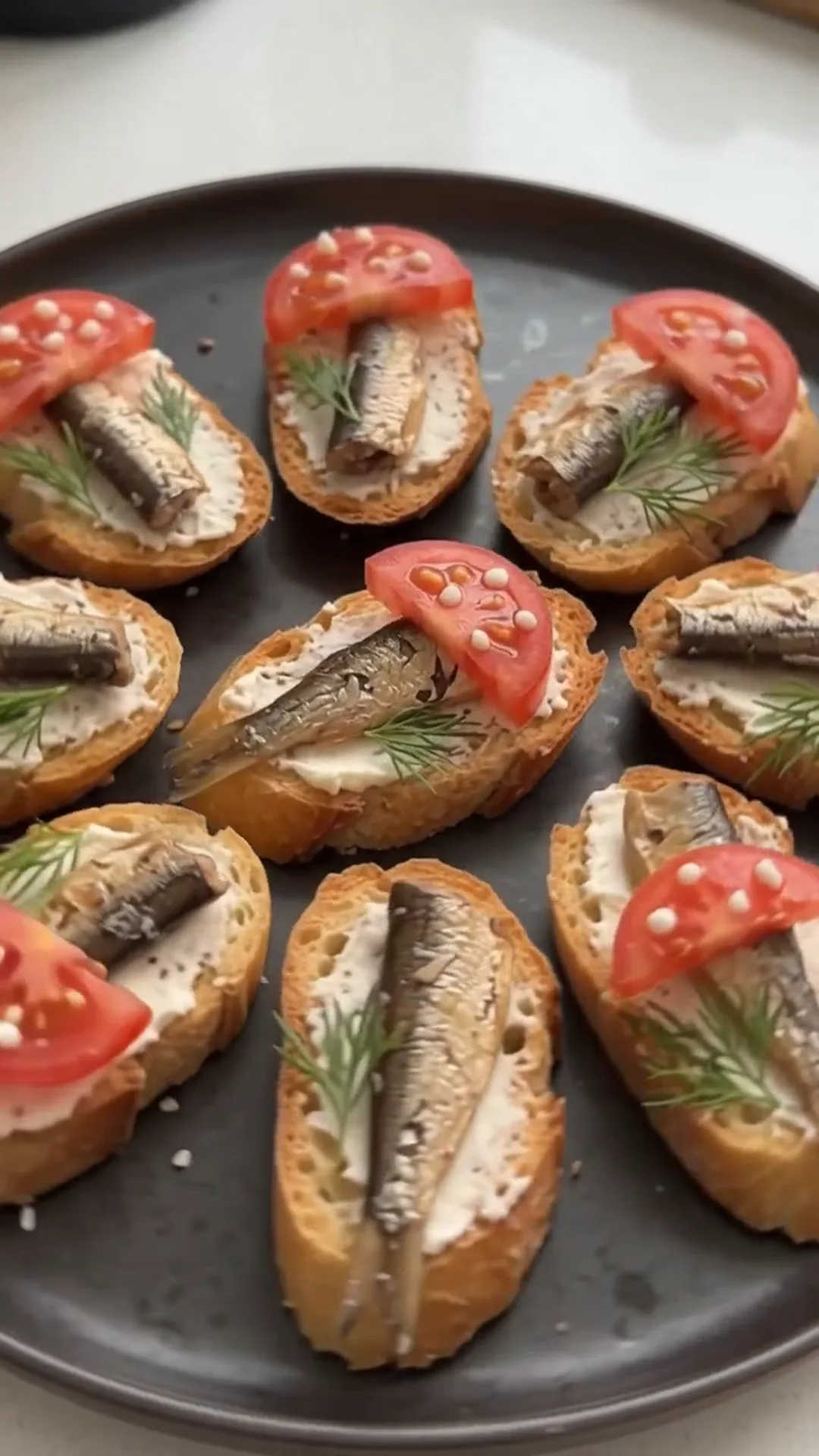 Smoked Sprat and Cream Cheese Baguette Bites – A person is preparing a dish with fish and tomatoes