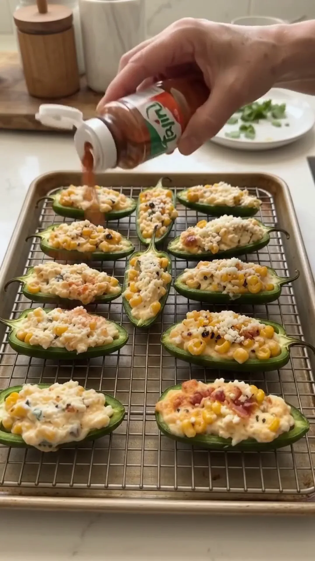 Spicy Mexican Street Corn Jalapeño Poppers Recipe – person is adding seasoning to stuffed jalapenos