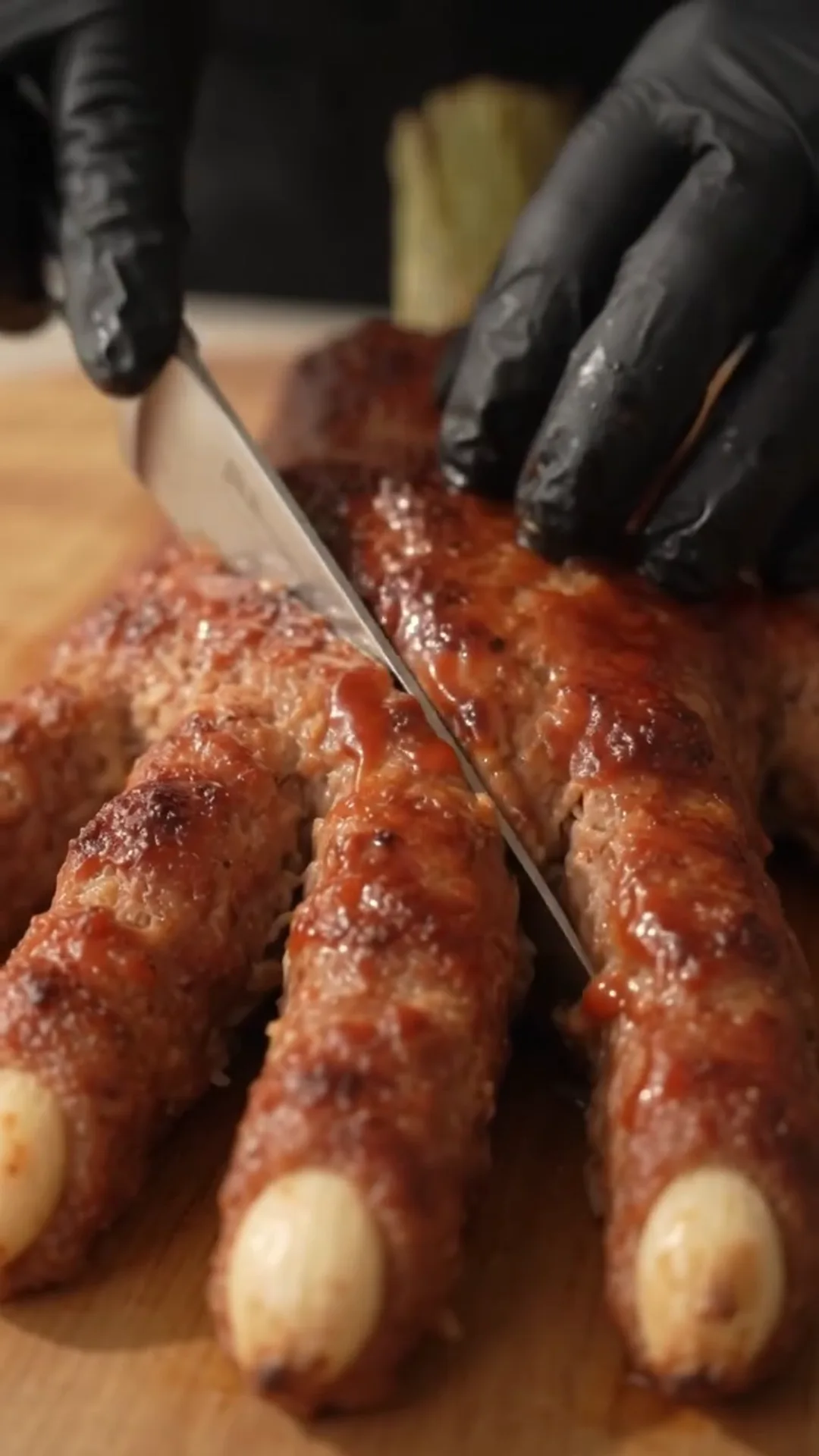 Spooky Halloween Hand Meatloaf Centerpiece – Someone is cutting a cooked meat dish with a knife