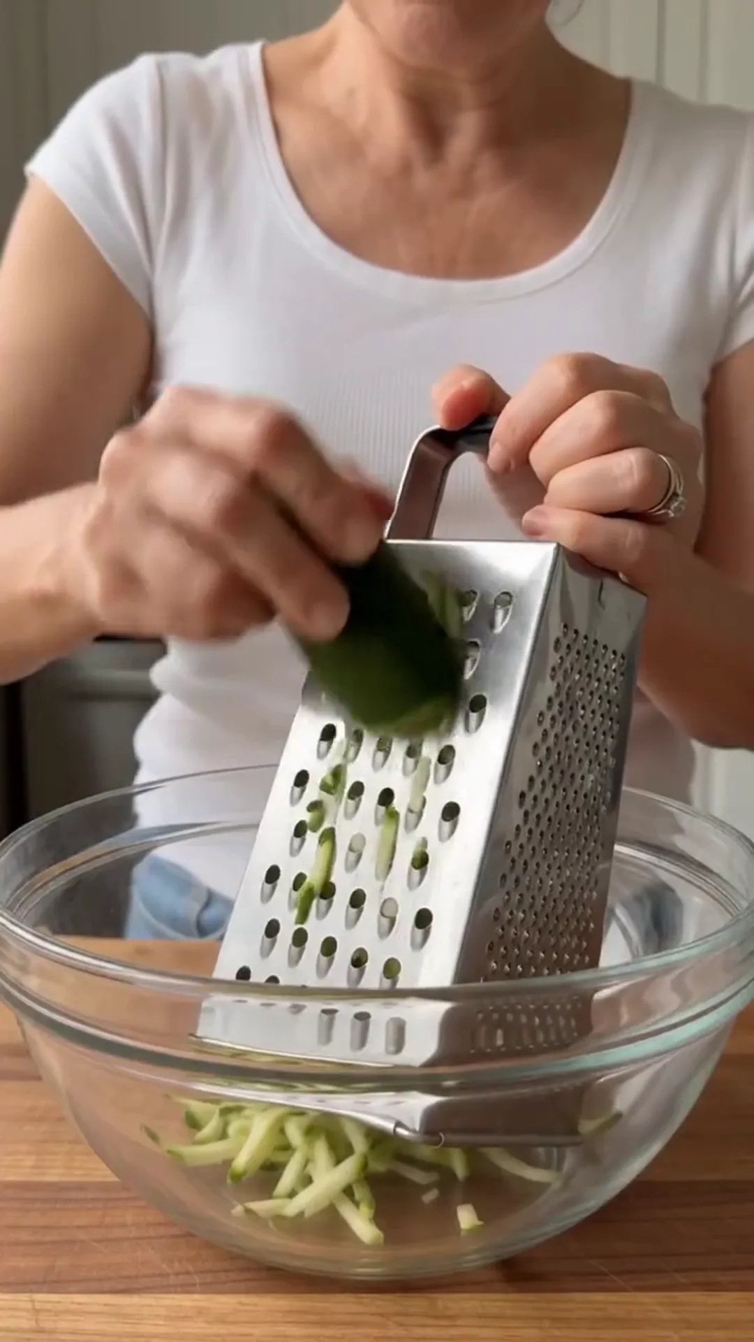 Zucchini Tawouk Flatbread with Savory Chicken – A woman is grating a vegetable into a bowl